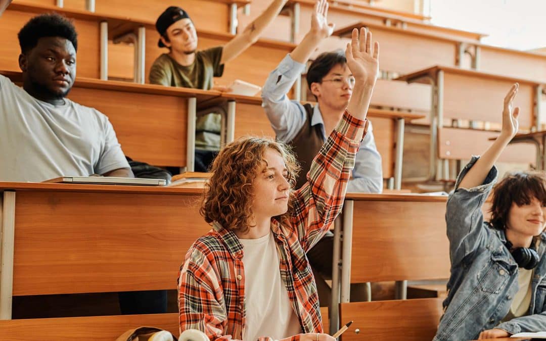 Several youthful interracial students raising hands to ask questions.