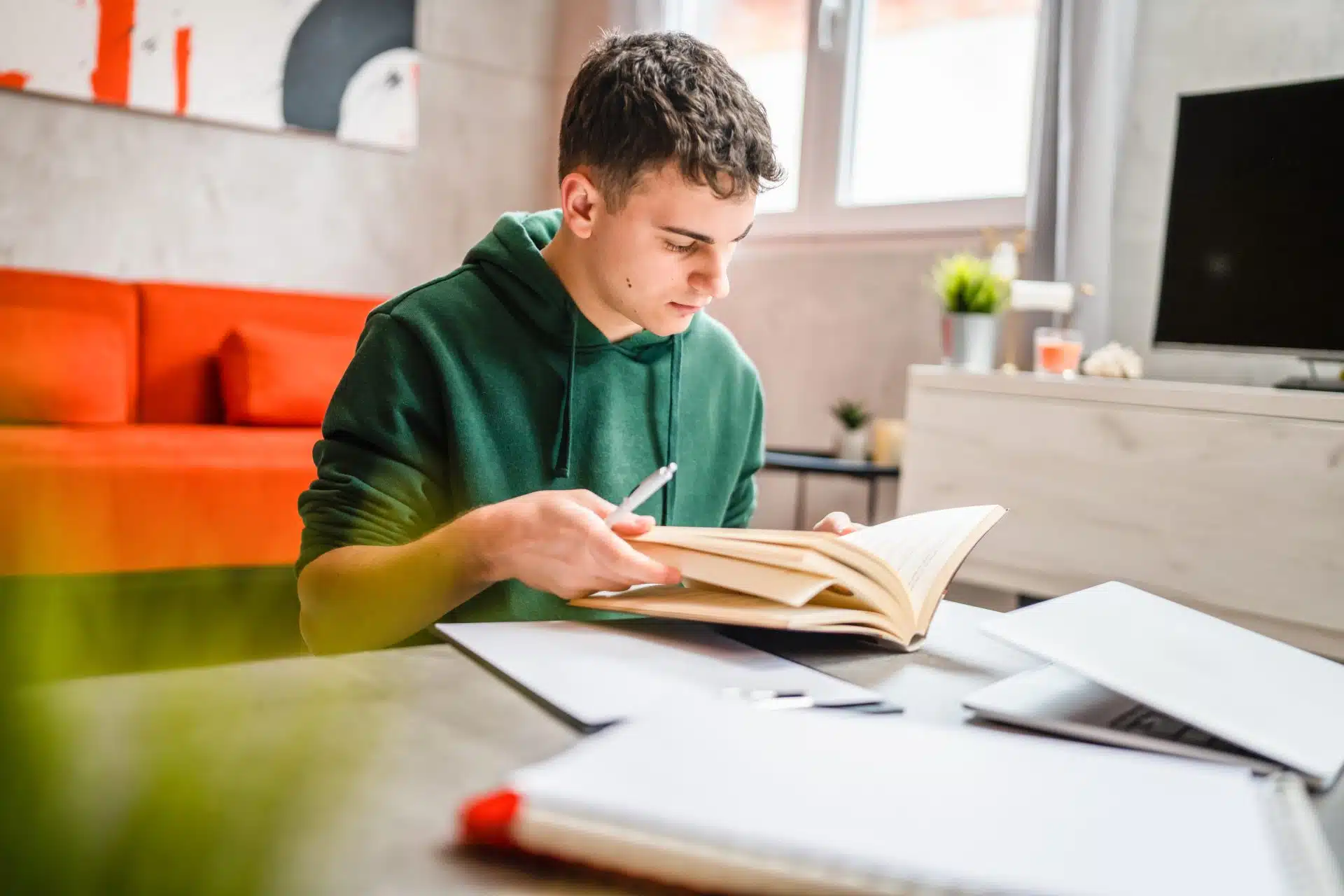 one young man caucasian teenager student learning study reading book while sitting at home prepare exam or work on project real people education concept copy space